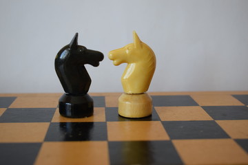 White and black chess knights on a chessboard