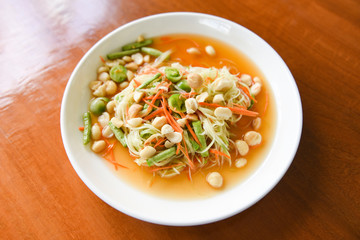 Thai food papaya salad with macadamia nuts on top on white plate / Healthy food
