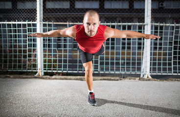 Athlete in a red t-shirt doing exercises at the outdoor gym.