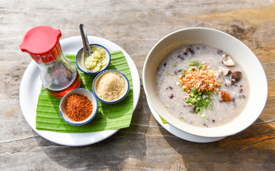 Mush or rice porridge - Boiled rice with pork shiitake mushrooms and vegetables with seasoning food sauce on wooden table