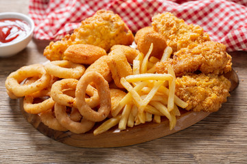 fast food meals : onion rings, french fries, chicken nuggets and fried chicken