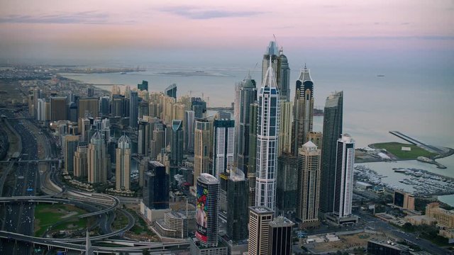Opens with a beautiful facade of Dubai Marina moving in close at the canal beside Cayenne Tower and pans by looking over rooftops of skyscrapers, 6-axis stabilized gimbal, Shotover F1, 8K.