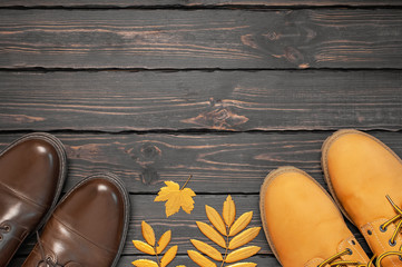 Brown classic leather men's shoes, Orange leather women boots, autumn golden leaves on dark wooden background top view. Autumn Fashion Concept. Fashionable footwear. Cozy fall composition. Sale, shoe