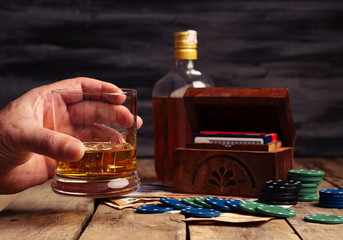 Banknotes next to poker chips, bottle, whiskey glass