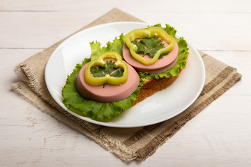 sandwich with sausage, lettuce and paprika rings