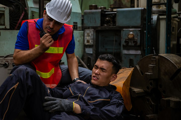 Young Asian man worker had a leg accident lying on the floor in metal lathe factory. Engineer...