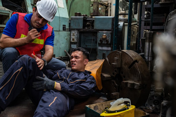 Young Asian man worker had a leg accident lying on the floor in metal lathe factory. Engineer...