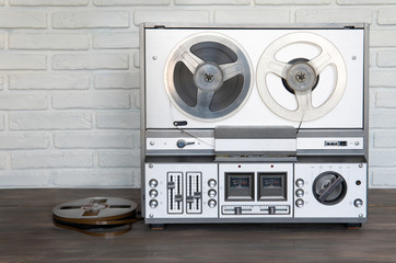 Stereo tape deck recorder player with reels on background.