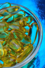 omega 3 capsule. In a glass bowl on a colored background.
