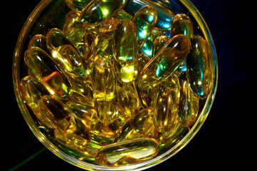 omega 3 capsule. In a glass bowl on a colored background.