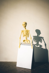 Skeleton and note paper on table, copy space for text, template for halloween.