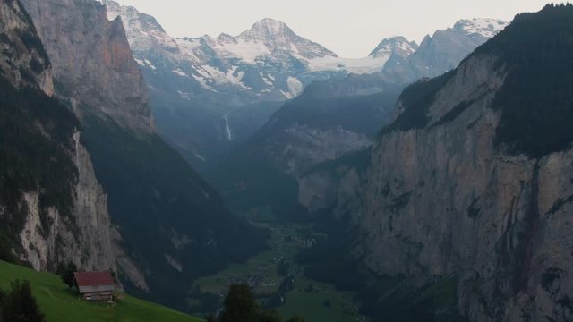 a lonely cabin sitting in front of a massive mountain in the swiss alps