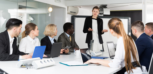 Fototapeta premium Young businesswoman making successful presentation to colleagues in meeting room.