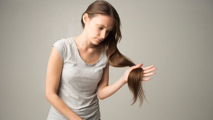 girl on a gray background holds a hair in her hand