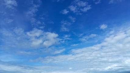 In a blue sky with light white translucent clouds, the wind is catching up to the horizon with clouds that completely cover the bright summer sky with a gray-white veil.