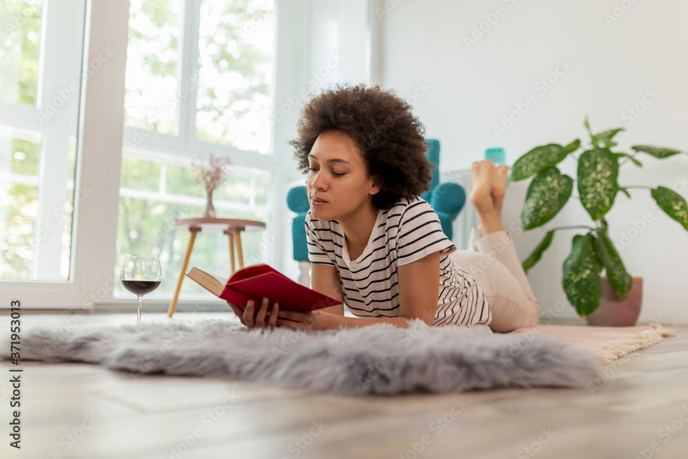 Wall mural Woman reading a book and drinking wine