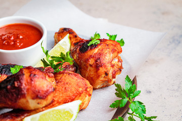 Baked chicken legs in tomato sauce or barbecue sauce on wooden plate.