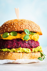 Vegan beetroot burger with sweet potato sauce and guacamole. Plant based diet concept.
