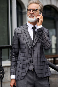portrait of elderly senior businessman dressed in formal elegant suit talking on mobile phone