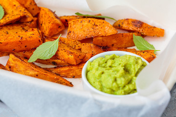 Baked sweet potato wedges with guacamole. Healthy vegan food concept.