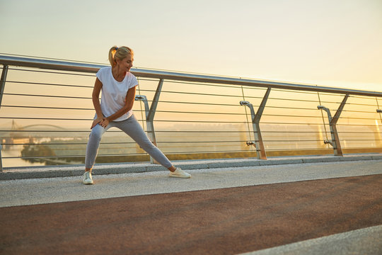 Charming woman stretching legs on the bridge - Powered by Adobe