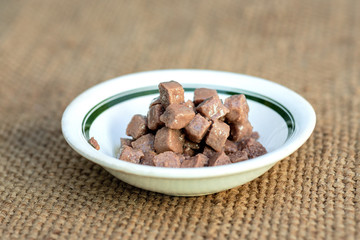cat food, pieces in jelly, a bowl of canned food for pets is on a mat on the floor