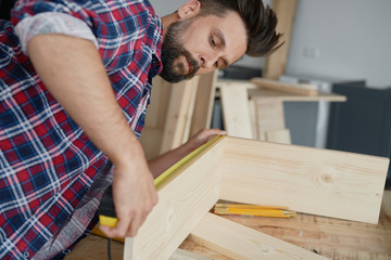 Fototapeta na wymiar Side view of carpenter measuring wooden plank