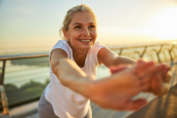 Cheerful woman doing exercise on the street