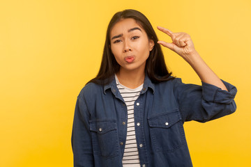 Too small! Portrait of displeased girl in denim shirt showing a little bit gesture, dissatisfied...