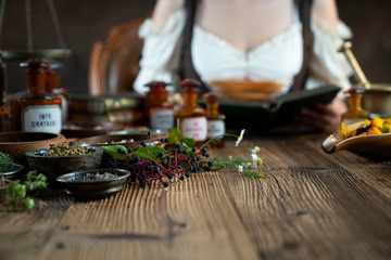 Natural medicine concept. Vintage pharmacist preparing natural medicament. Brass mortar and  bottles. Rustic table. Assorted dry herbs in bowls.