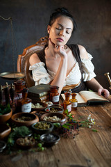 Natural medicine concept. Vintage pharmacist preparing natural medicament. Brass mortar and  bottles. Rustic table. Assorted dry herbs in bowls.