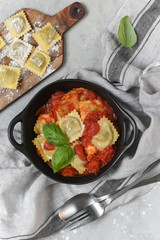 Ravioli tomato sauce with basil on black pan. top view, recipe  Italian cuisine.