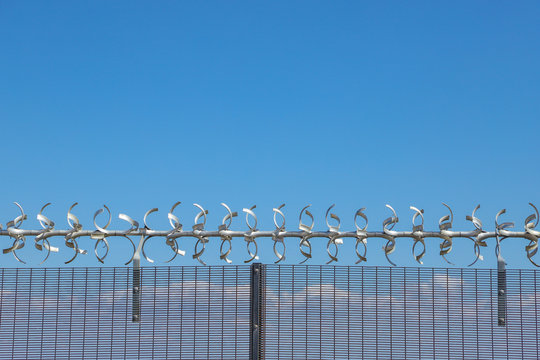 Restricted area.  Close up of barbed wire security fence against a blue sky