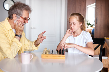 playing chess perfectly unites generations, grandfather and granddaughter spend time together at home