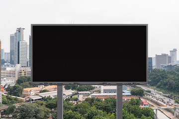 Blank black road billboard with Kuala Lumpur cityscape background at day time. Street advertising poster, mock up, 3D rendering. Front view. Concept of marketing to promote or sell services or ideas.