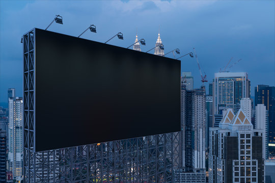 Blank black road billboard with KL cityscape background at night time. Street advertising poster, mock up, 3D rendering. Side view. The concept of marketing communication to promote or sell idea.