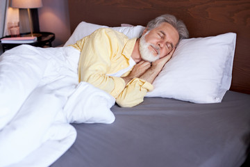 calm senior male have good dreams, sleep. lie on bed in the morning