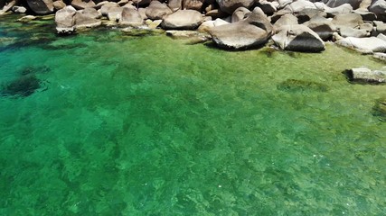 Calm sea water near stones. Peaceful blue sea water and gray boulders in perfect place for snorkeling on Koh Tao Island on sunny day in Thailand. Natural background texture.