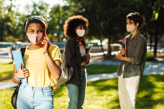 Image of multinational student girls talking on cellphone while walking