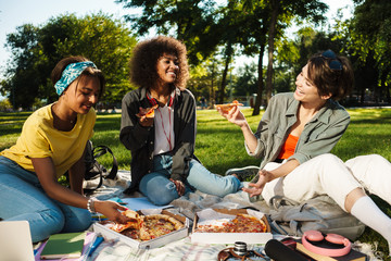 Image of funny nice student girls eating pizza while doing homework