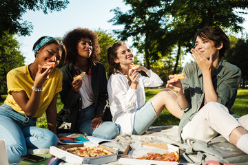 Image of funny nice student girls eating pizza while doing homework