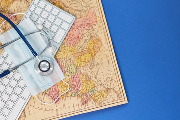 Keyboard, medical stethoscope and a protective mask on a geographical map. Concept stay home and remote work. medicine, hospital, safety, epidemic, doctor's call, online, consultation. Banner.