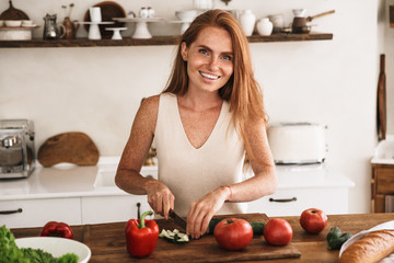 Obraz na płótnie Canvas Smiling attractive young woman making a salad