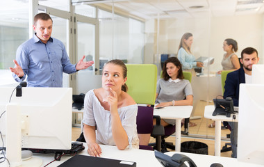 Irritated adult boss scolding young female subordinate pointing out shortcomings and misses in work