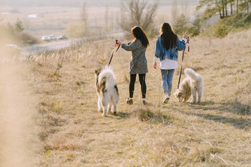 Women in a spring forest. Girls with cute dogs. Stylish friends walks.