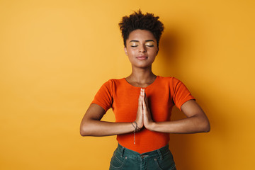 Image of african american woman meditating and holding palms together