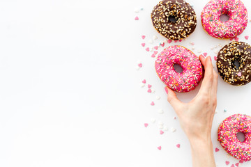 Hand holding glazed donut swith sprinkles, above view