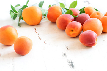Fresh sweet apricots on the white rustic table closeup. Healthy sweet fruits, harvest time.