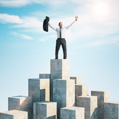 Happy businessman standing on cube