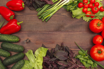 Tomatoes, cucumbers, bellpeppers, lettuce, basil and leek on a rustic table. View from above.